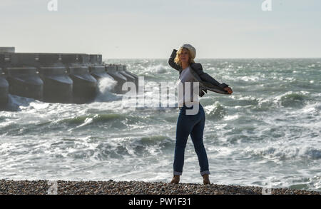 Brighton UK 12 octobre 2018 - Une femme se bloque sur son chapeau pour qu'elle bénéficie d'une promenade le long de la plage de Brighton, ce matin, à des vents forts que Storm Callum balaie certaines parties de la Grande-Bretagne aujourd'hui Crédit : Simon Dack/Alamy Live News Banque D'Images