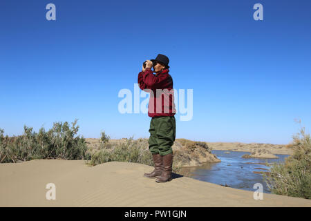 (181012) -- EJINA BANNER, 12 octobre 2018 (Xinhua) -- Interdiction Du, un 81-year-old bouvier de l'ethnie mongole, vérifie les conditions d'entreposage de l'eau d'un barrage en Ceke Gacha de bannière Ejina, Chine du nord, région autonome de Mongolie intérieure, le 11 octobre 2018. Ceke Gacha, un village dans le désert de Badain Jaran, est connue pour son climat sec et l'environnement difficile. Cependant, l'interdiction du, contrairement à d'autres bergers, n'est pas prêt à quitter sa ville natale et d'être transférée dans une maison de ville offerts par le gouvernement local. Il a contracté une prairie dans le désert, et il s'occupe de la siècle-vieux peupliers coveri désert Banque D'Images