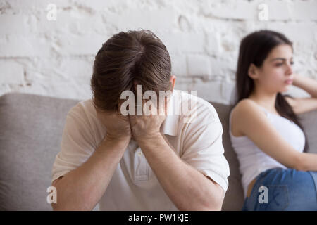 Malheureux jeune homme et femme en querelle sitting on couch Banque D'Images