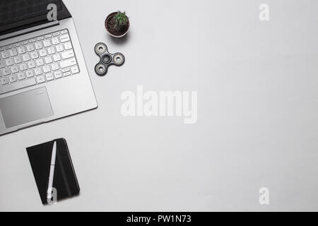 Bureau minimaliste moderne ou d'offres de l'espace de travail. Vue d'en haut. Copier l'espace. Mise à plat. La composition avec coffre, cactus, ordinateur portable avec stylo et fidget spinn Banque D'Images