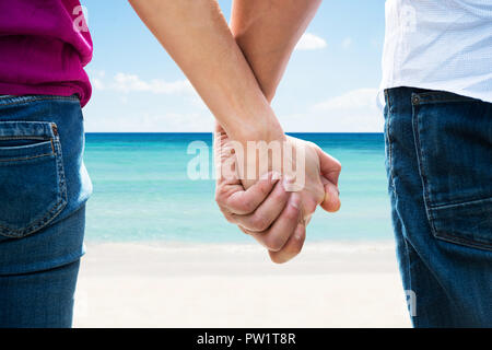Close-up of a couple Holding Hands à Sandy Beach Banque D'Images