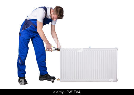 Homme Plumber Repairing Thermostat avec Clé sur fond blanc Banque D'Images