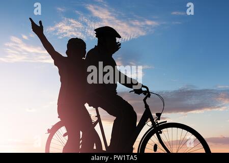 Silhouette d'un couple en vélo au coucher du soleil Banque D'Images