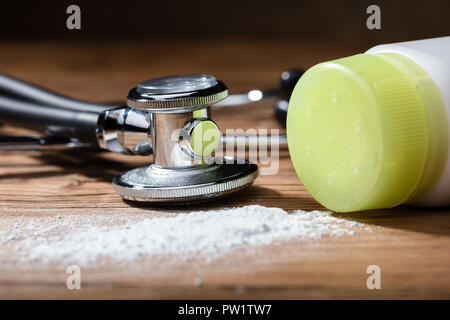 Close-up du produit répandu de la poudre de talc et stéthoscope sur fond de bois Banque D'Images