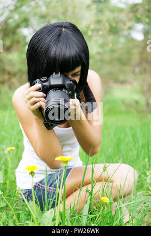 jeune femme prenant la photo de pissenlit dans la nature Banque D'Images