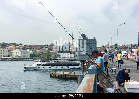 Un groupe de pêcheurs sur le pont de Galata avec leurs cannes à pêche sur le côté comme un laissez-passer de traversier par, Istanbul, Turquie Banque D'Images