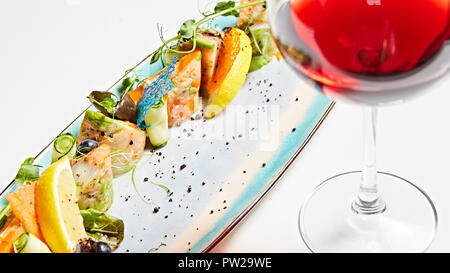 Rouleaux de poisson frit avec des herbes et des légumes sur la plaque bleue. Banque D'Images