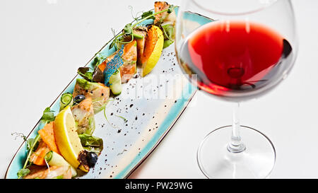 Rouleaux de poisson frit avec des herbes et des légumes sur la plaque bleue. Banque D'Images