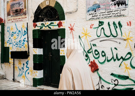 Jérusalem, Israël. 11 octobre, 2018. Une femme Arabe Musulmane passe devant l'entrée d'une maison décorée pour accueillir ceux qui reviennent d'un haj à La Mecque dans la vieille ville de Jérusalem le quartier musulman. Banque D'Images