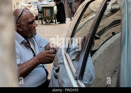Jérusalem, Israël. 11 octobre, 2018. Un vieil homme musulman arabe, s'allume une cigarette près de la porte de la chaîne du Mont du Temple à Jérusalem. Banque D'Images