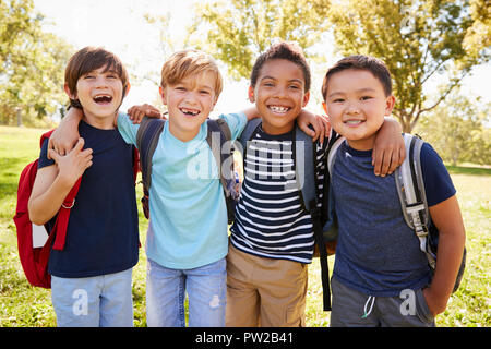 Quatre jeunes écoliers souriants sortir sur un voyage scolaire Banque D'Images