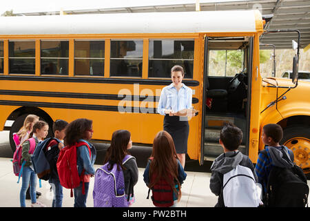 Enseignant en tenant un registre des enfants de l'école par autobus scolaire Banque D'Images