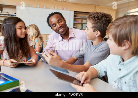 Aider les enfants de l'école enseignant à l'aide de tablet computers in class Banque D'Images