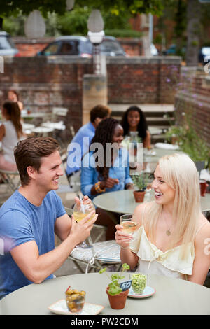 Couple assis à table en verre avec jardin Pub Banque D'Images