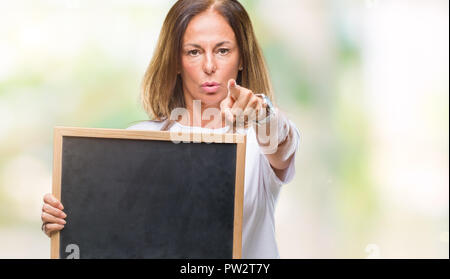 L'âge moyen hispanic woman holding tableau noir sur fond isolé pointant avec le doigt à la caméra et à la main, vous signe, positif et confiant Banque D'Images