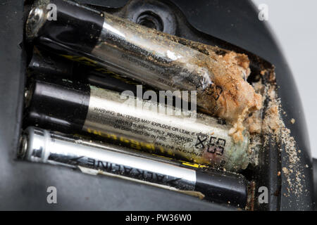 Une pile alcaline AAA qui a été laissée pendant plusieurs années dans une paire d'audience électronique humains et d'une fuite à l'extrémité négative de la batterie Banque D'Images