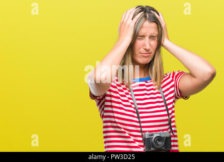 Belle jeune femme prendre des photos à l'aide de l'appareil photo vintage sur fond isolés souffrant de maux désespérés et souligné parce que la douleur Banque D'Images