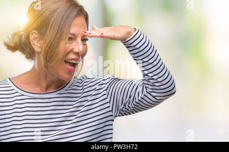 L'âge moyen senior hispanic woman sur fond isolé très heureux et souriant à loin avec la main sur la tête. Concept de la recherche. Banque D'Images