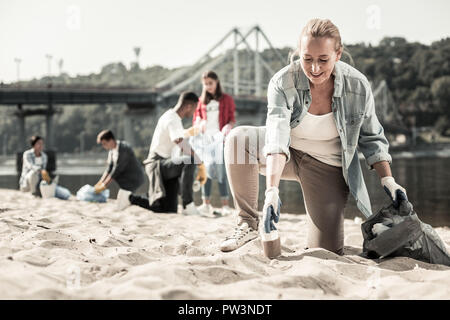 Transmission de blonde-haired woman wearing denim shirt bénévolat près de la rivière Banque D'Images