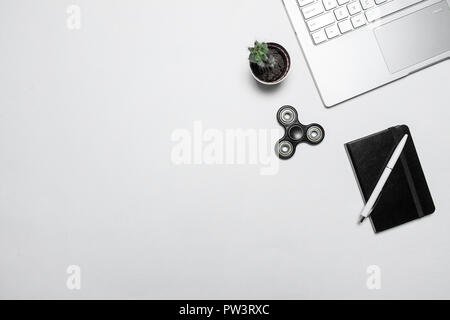 Un minimum d'espace de travail moderne. La composition avec coffre, cactus, ordinateur portable avec stylo et fidget spinner isolé sur blanc 24. Haut de la vue, télévision lay. Banque D'Images