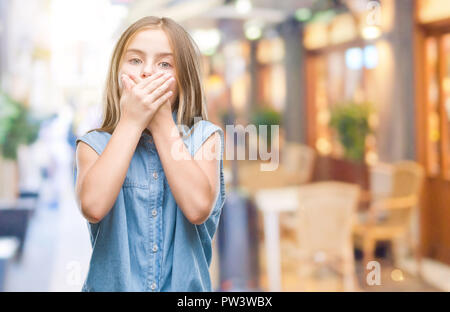 Belle jeune fille sur fond isolé choqué couvrant la bouche avec les mains pour l'erreur. Concept Secret. Banque D'Images