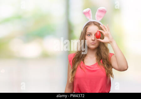 Jeune femme blonde portant des oreilles de lapin de pâques avec une expression confiante face à la pensée intelligente grave Banque D'Images