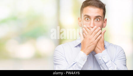 Beau jeune homme choqué couvrant la bouche avec les mains pour l'erreur. Concept Secret. Banque D'Images