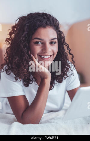 Dark-eyed girl smiling bouclés tout en regardant des photos Banque D'Images
