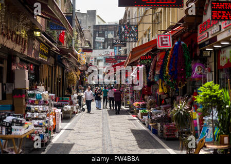 Les gens marcher dans une rue pavée de petits magasins avec des marchandises sur l'affichage, Istanbul, Turquie Banque D'Images