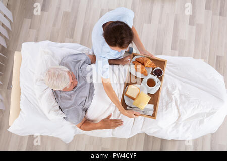 Vue supérieure de l'infirmière qui sert de nourriture pour Senior Male Patient dans un centre Banque D'Images