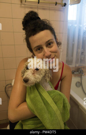 La femme donne son chien d'une baignoire et de shampoing dans la baignoire à la maison. Banque D'Images