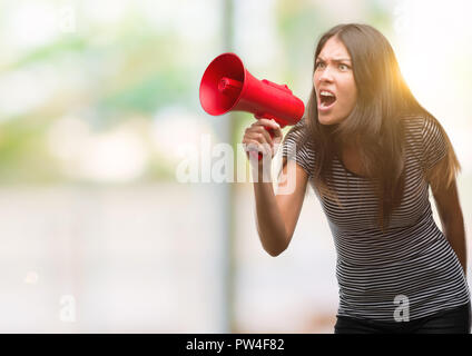 Young hispanic woman holding megaphone contrarié et frustré de crier avec colère, fou et hurlant de main levée, la colère concept Banque D'Images