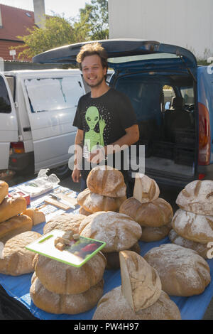 Jeune homme vend du pain artisanal à un marché de producteurs à Zielona Gora, Pologne. Banque D'Images