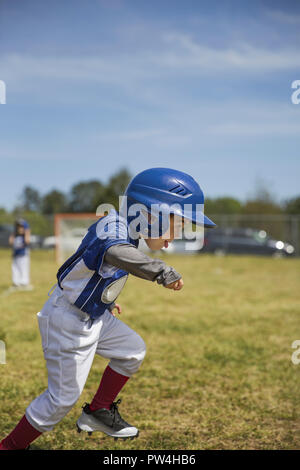 Vue latérale du joueur de baseball s'exécutant sur grassy field against sky Banque D'Images