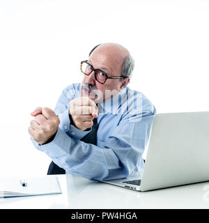 1960 senior businessman patron furieux hurlant et gesticulant contrarié et mad sitting on desk dans la gestion et problèmes de stress au travail isolé sur bac blanc Banque D'Images