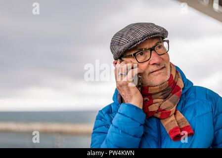 Close-up of senior man talking on smart phone en position debout par mer contre ciel nuageux Banque D'Images