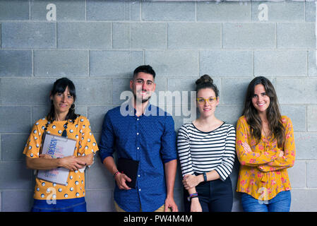 Portrait of business people standing against wall in creative office Banque D'Images