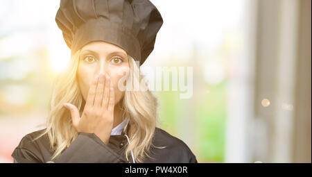 Belle femme chef cuisinier se couvrir la bouche sous le choc, l'air timide, exprimant le silence et l'erreur, peur des concepts Banque D'Images