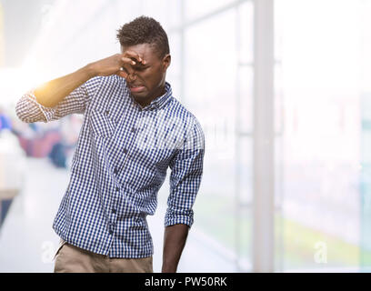 Young african american man wearing blue shirt humer un stinky et dégoûtant, odeur insupportable, apnée avec les doigts sur le nez. Mauvais sm Banque D'Images