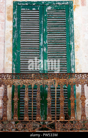 Un vieux volet vert avec rusty balcon dans la ville italienne de Ceglie dans la région des Pouilles en Italie. Banque D'Images