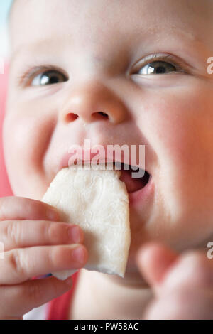 Un an Alexander James mange une galette de banane sur une chaise haute Banque D'Images