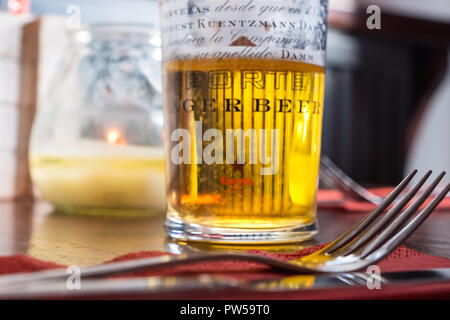 La moitié ivre verre de bière blonde et d'une fourchette sur une table dans un bar Banque D'Images
