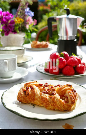 Dimanche matin ensoleillé petit déjeuner servi en plein air jardin d'été avec des produits frais de boulangerie et fraise close up Banque D'Images