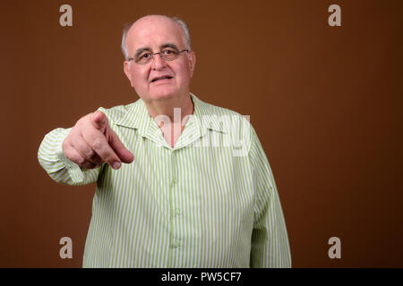 L'embonpoint senior man wearing eyeglasses contre brown backgroun Banque D'Images