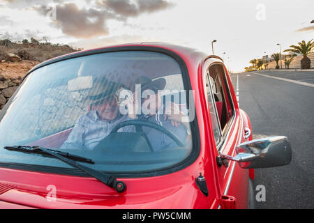 Joli couple hug et de l'amour à l'intérieur d'un vieux millésime rouge voiture garée sur la route. sourit et s'amuser voyageant ensemble. Le bonheur et le mode de vie pour le ni Banque D'Images