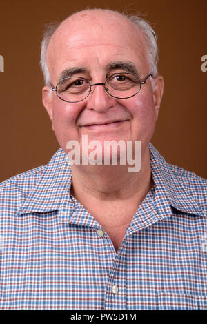 L'embonpoint senior man wearing eyeglasses contre brown backgroun Banque D'Images