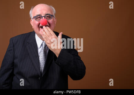 L'embonpoint senior businessman wearing red clown nose Banque D'Images