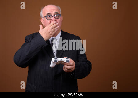 L'embonpoint senior businessman holding jeux et contrôleur de jeu Banque D'Images