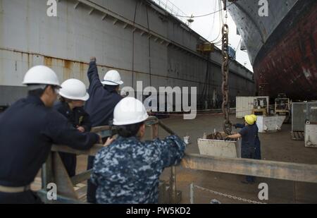 SAN DIEGO (sept. 21, 2017) Les marins affectés au navire d'assaut amphibie USS Makin Island (DG 8) observer le décharger de la chaîne d'ancre tribord. Makin Island est actuellement en cale sèche à General Dynamics et de l'Acier National Shipbuilding Company (NASSCO) pour un dépôt d'entretien au niveau de disponibilité. Banque D'Images