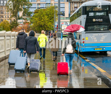 Waverley Bridge, Edinburgh, Ecosse, Royaume-Uni, 12 octobre 2018. Royaume-uni : La pluie météo annonce l'arrivée de Storm Callum dans la capitale, mais n'a pas dissuader les touristes. Les brise-vent une femme. Les touristes à pied sous la pluie avec les valises à l'aéroport service de bus 100 Banque D'Images